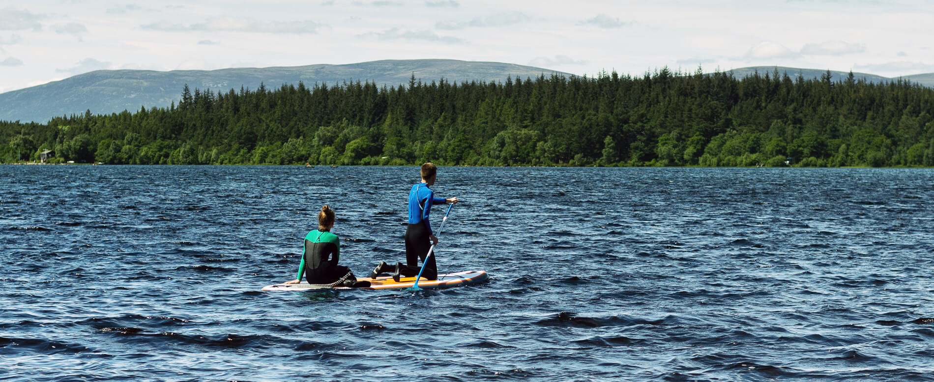 Couple paddle boarding in Scotland