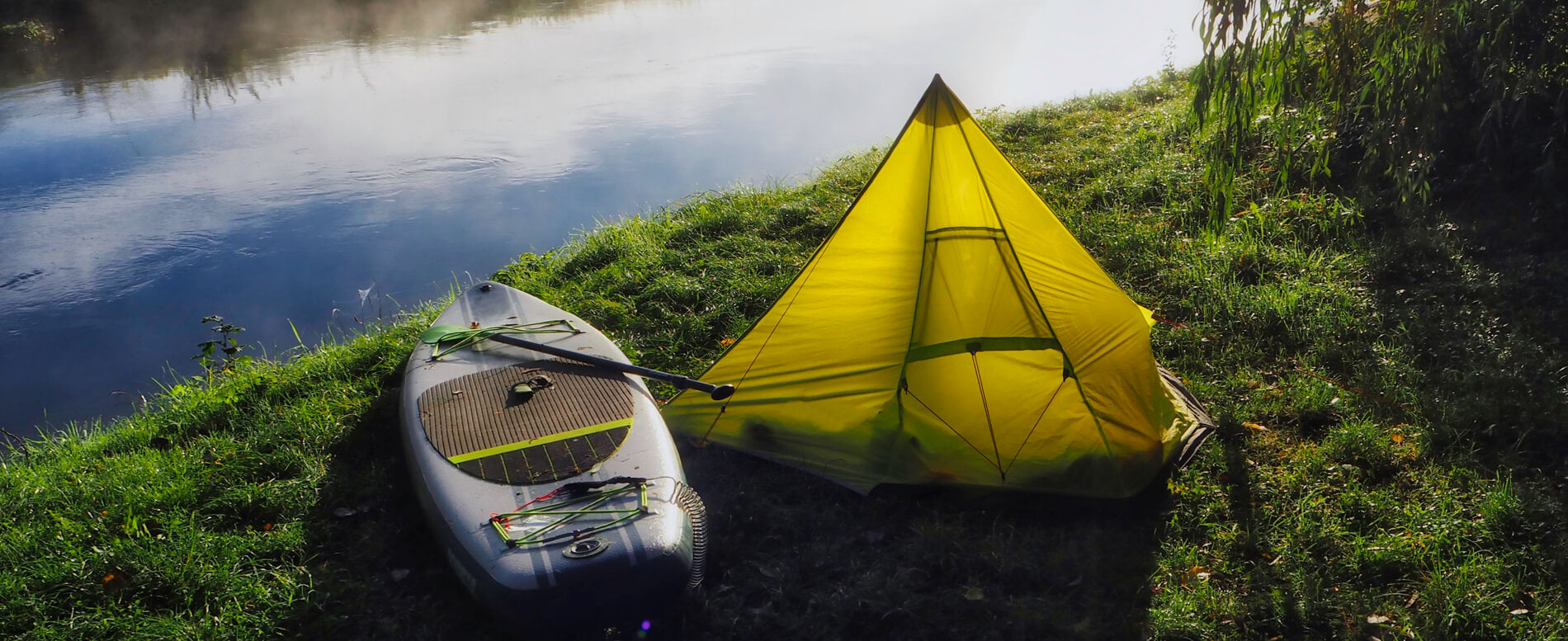 Yellow camping tent beside an inflatable paddle board