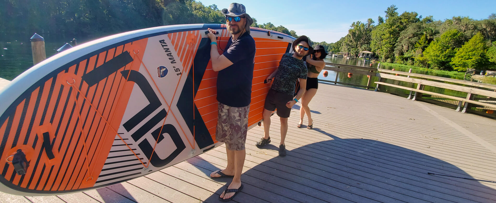 A group of friends holding a multi person inflatable paddle board