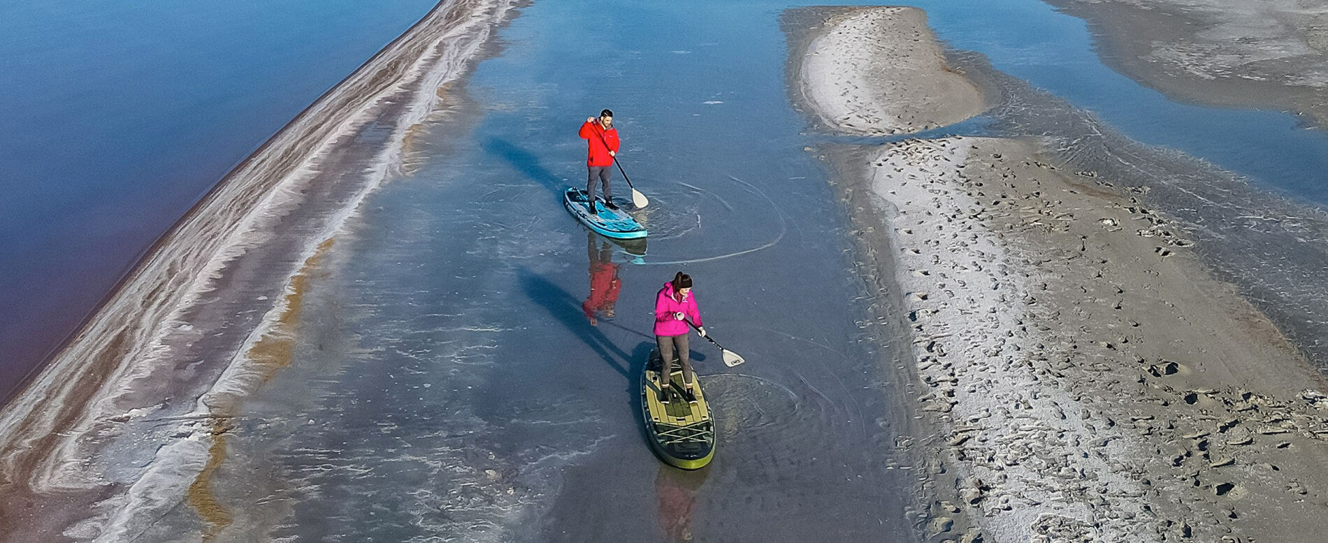 Couple with complete winter gear while paddle boarding