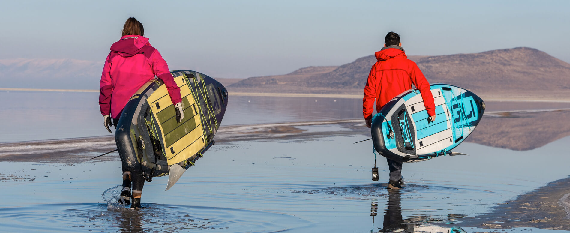 Man and a woman carrying their blue and camo inflatable paddle board